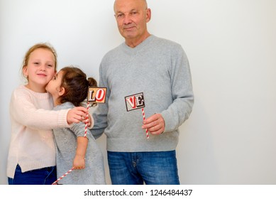 Two generations, Multi race love family. Beautiful People Celebrating Holiday. Portrait Happy Cool Grandpa having time with his cute funny granddaughters. Copy space.Girl kissing her sister in cheek.