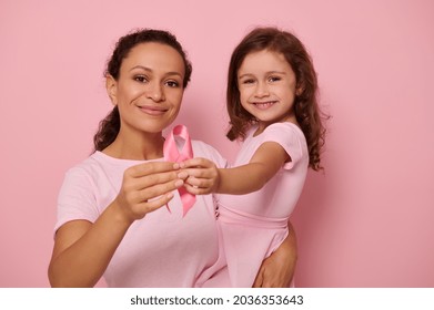 Two generations of women, mom and daughter hugging each other, holding pink ribbon, Breast Cancer Awareness Day symbol, showing support and solidarity to cancer patients and survivors. Women's health - Shutterstock ID 2036353643