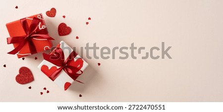 Two gift boxes wrapped in red and white with ribbons sit among scattered hearts on a soft beige background, conveying love, romance, gift exchange, and heartfelt greetings for Valentine’s Day