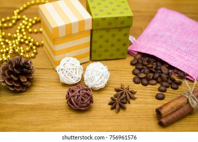 Two gift boxes - yellow and green, fir cones, balls of vine and coffee beans in a pink pouch on a wooden table - Powered by Shutterstock