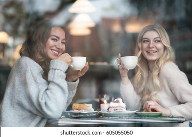 Two Girl Friends Drinking Coffee In The Cafe