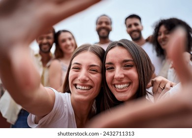 Two girl friends making a frame with hands. A group of young people is happily celebrating, taking a selfie together. Smiling women having fun during their leisure travel - Powered by Shutterstock