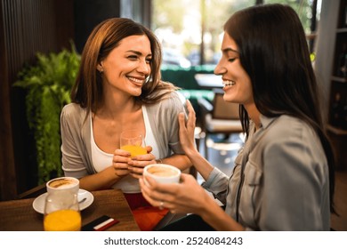 Two girl friends met at the coffee shop to hang out, gossip and talk to each other. They are drinking coffee and orange juice. - Powered by Shutterstock