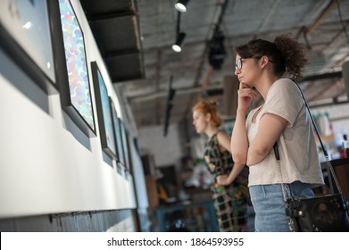 Two Girl Friends In Modern Art Exhibition Gallery Hall Contemplating Artwork. Abstract Painting