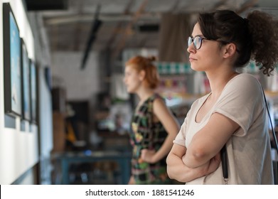 Two Girl Friends In Modern Art Exhibition Gallery Hall Contemplating Artwork. Abstract Painting