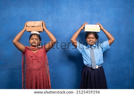 Two girl kids with books and bricks on each other head looking at camera - concept poverty and conflict or necessary between education and child labour.