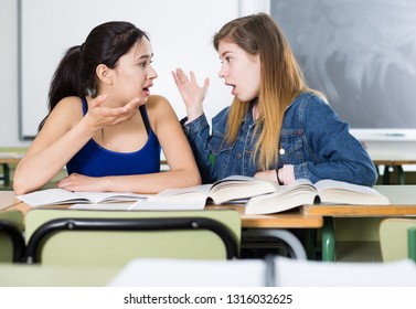 Two Girl Are Sitting At The Desk And Talking About Life In The Classroom.