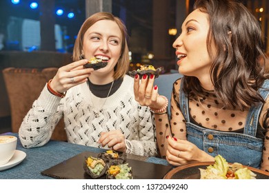 Two girlfriend girls chat and laugh in the restaurant and eat Spanish tapas. Concept of friendship and relations