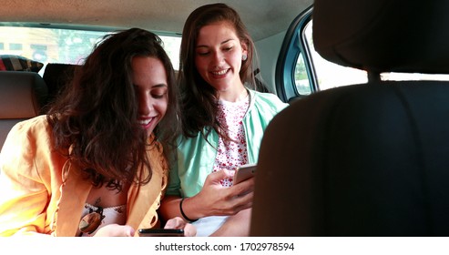 
Two Girlfriends In Backseat Of Car Taking Photo Of Each Other. Girl Smiling And Posing To Photo