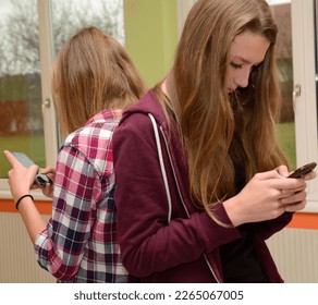 Two girlfriends communicate back to back over the phone