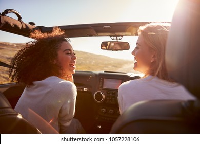 Two Girlfriends Driving With Sunroof Open Look At Each Other