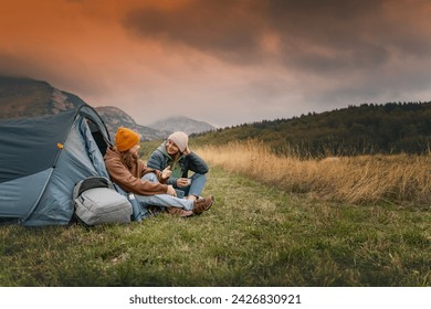 Two girlfriends, a lesbian couple, traveling together in the mountains with a tent. Camping active lifestyle  - Powered by Shutterstock