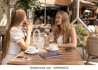 Two Girlfriends Talking In A Outside Cafe Bar