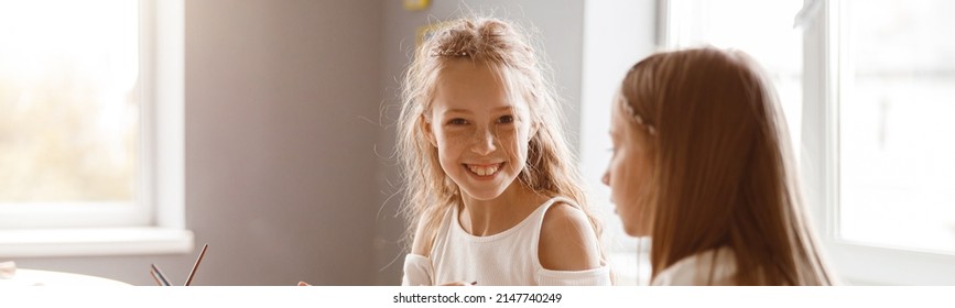 Two Girlfriends Talking While Painting With Watercolors At School