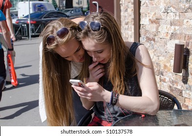 Two girlfriends are using cellphone in the cafe