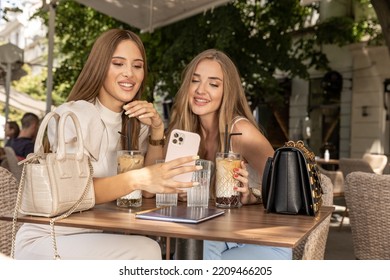 Two girlfriends using smartphone in a cafe bar