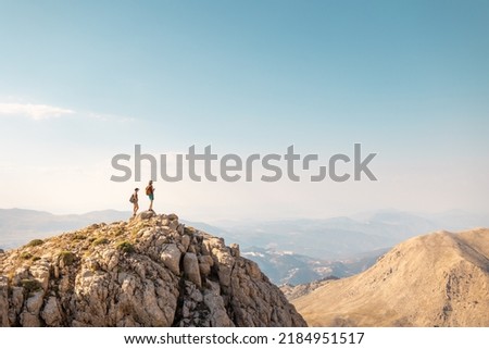 two girls with backpacks stand on top of a mountain. hiking and adventure vacation. climbing and freedom.