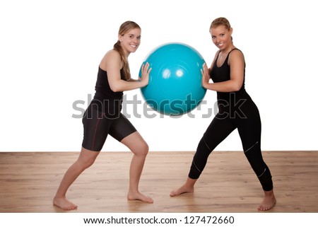 Two girls balancing a blue exercise ball