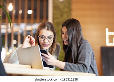 two girls in a cafe with a tablet and laptop