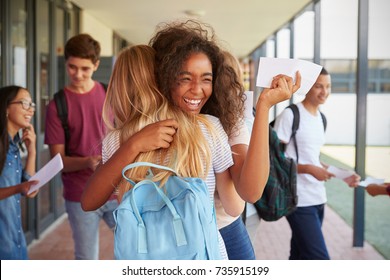 Two girls celebrating exam results in school corridor