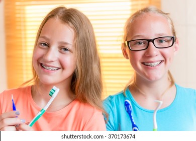 Two girls with dental retainers brushing teeth