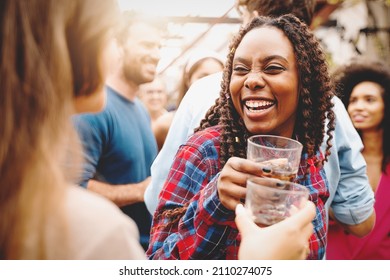 Two Girls Of Different Races Toast Together At The College End-of-year Party - Biracial Friends Who Get Together Having Fun On The Dance Floor On The Terrace Drinking And Dancing Together.