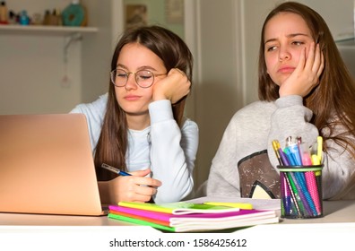 Two Girls Do Homework With The Help Of The Laptop. Too Much Information Can Bring Fatigue And Exhaustion. The Concept Of Communication And Navigation, The Internet, Social Network.