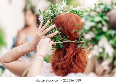 Two Girls Dress Each Other With A Wreath Of Wildflowers. Weaving A Wreath. A Young Pagan Slavic Girl Performs A Ceremony On Midsummer Day. Earth Day