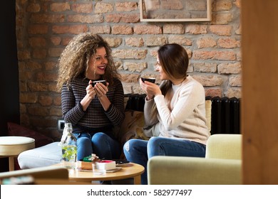 Two Girls Are Drinking Coffe In A Cafe.