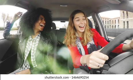 Two Girls Driving In A Car Laughing And Having Fun. Afro Girl With Blonde Enjoying A Car Ride.