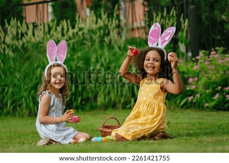 two girls during Easter egg hunt and putting Easter eggs in baskets