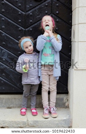 Two girls eat candy on a stick.
