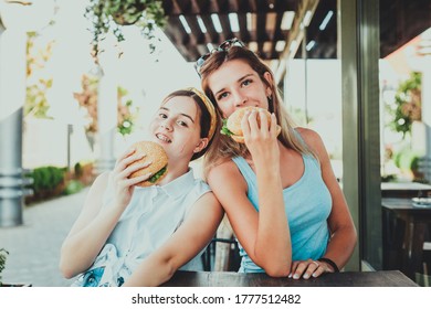 Two Girls Eating Burgers In A Street Cafe