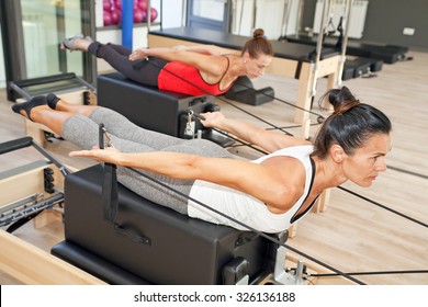 Two girls are exercising pilates using pilates device reformer