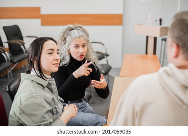 Two Girls And A Guy Are Talking In Sign Language. Three Deaf Students Chatting In A University Classroom.