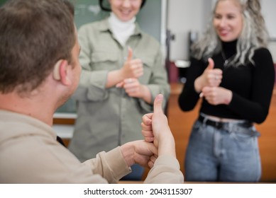 Two girls and a guy are talking in sign language. Three deaf students chatting in a university classroom. - Powered by Shutterstock