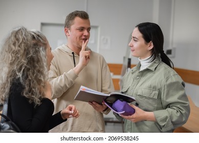 Two Girls And A Guy Are Talking In Sign Language. Three Deaf Students Chatting In A University Classroom.