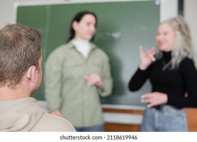 Two Girls And A Guy Are Talking In Sign Language. Three Deaf Students Chatting In A University Classroom.