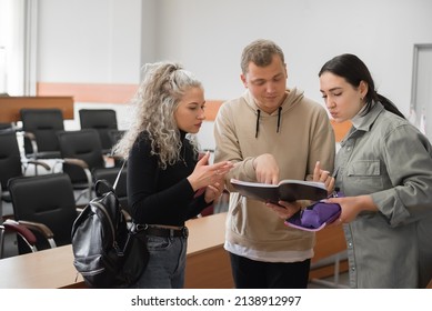 Two Girls And A Guy Are Talking In Sign Language. Three Deaf Students Chatting In A University Classroom.