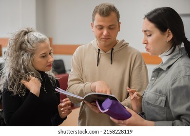 Two Girls And A Guy Are Talking In Sign Language. Three Deaf Students Chatting In A University Classroom.