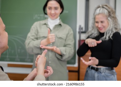 Two Girls And A Guy Are Talking In Sign Language. Three Deaf Students Chatting In A University Classroom.