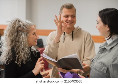 Two Girls And A Guy Are Talking In Sign Language. Three Deaf Students Chatting In A University Classroom.