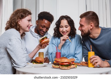 Two Girls And Two Guys Laughing At The Table Having Food And Drinks In Their Hands