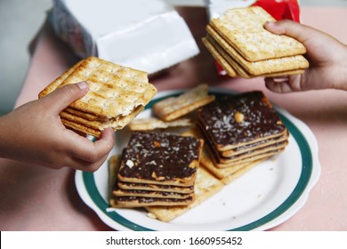 Two Girls' Hands Sharing Chocolate Biscuits