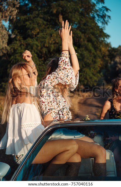 Two girls\
have fun on the car in the\
countryside
