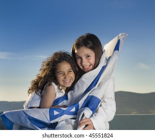 two girls holding hugging the Israeli flag