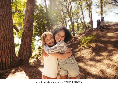 Two Girls Hugging Each Other Outdoors. Kids Together In Forest Having A Great Time.