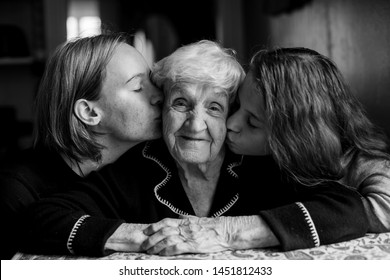 Two Girls Kiss Their Grandmother. Black And White Portrait.