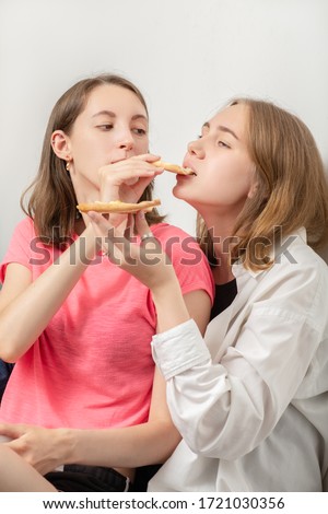 two girls lesbians eats pizza sitting on floor, laughing