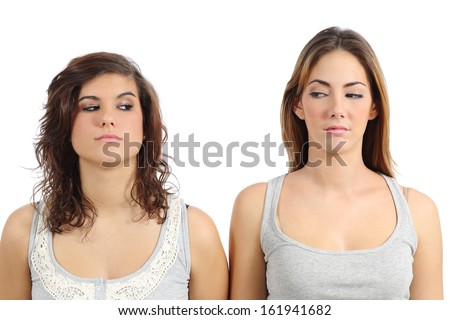 Two girls looking each other angry isolated on a white background